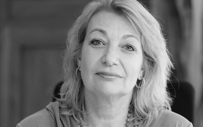 katrin-reuter-blog-blocages-adultes Portrait of a smiling middle-aged woman with shoulder-length light hair and hoop earrings as a headshot.